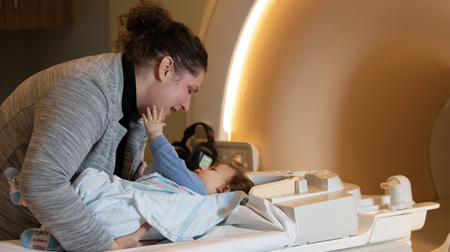 Research investigator Jessica Wisnowski, PhD placing infant into diagnostic machine