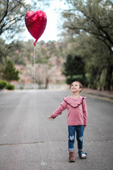 Emme outdoors holding a heart-shaped balloon