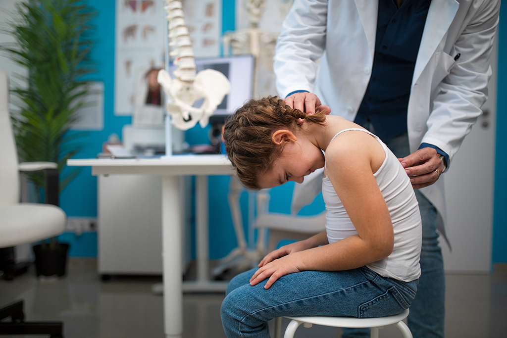 Orthopedic doctor checks little girl's spine
