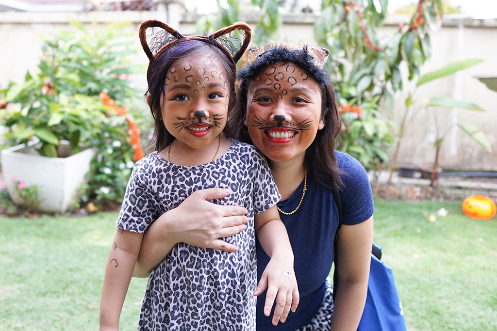 Mother and daughter smile with their faces painted to look like cats