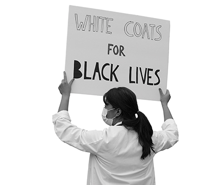 Female physician holding a sign that reads White Coats for Black Lives