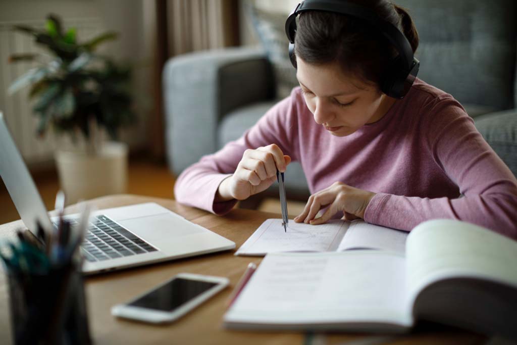 Young girl wearing headphones while doing homework